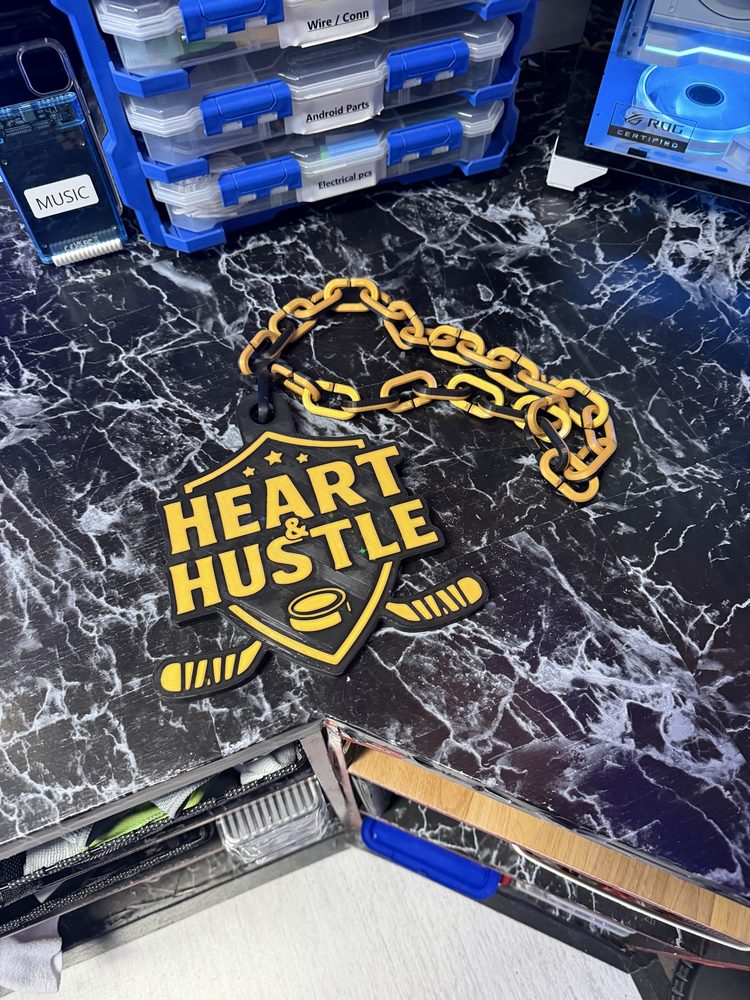 Black and gold Heart and Hustle hockey medal on a printed chain