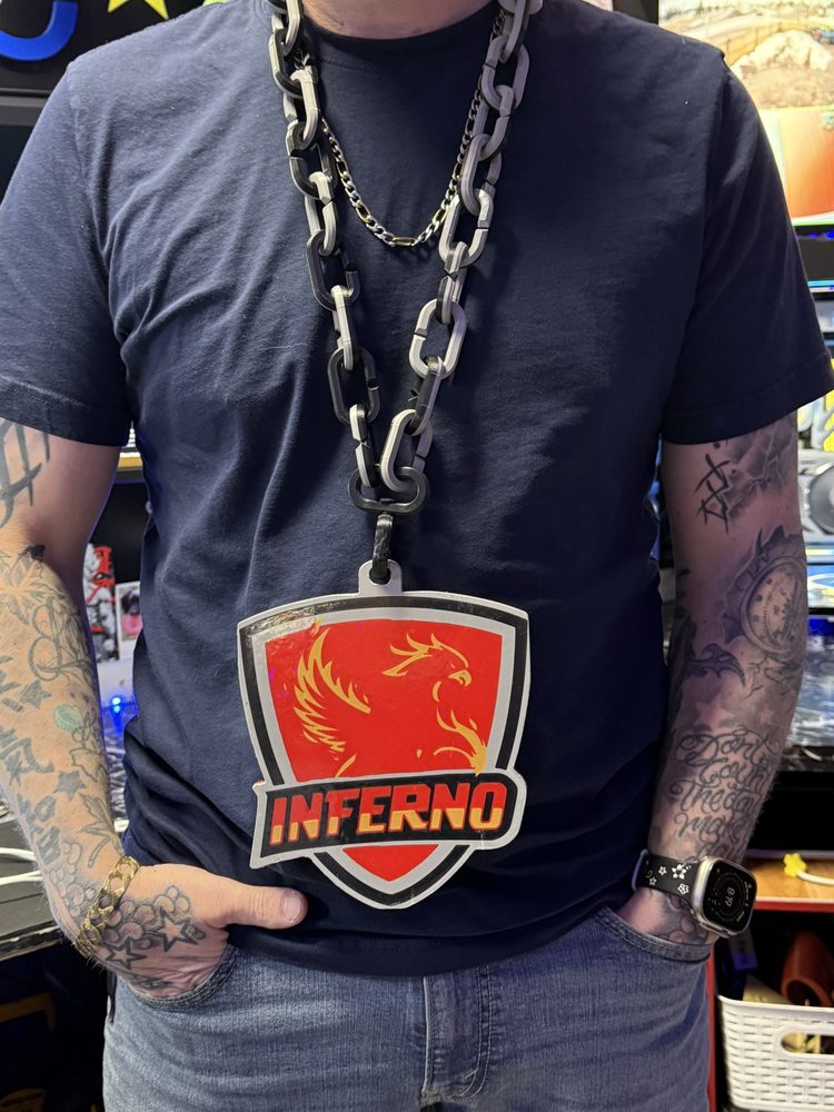 Person wearing the Inferno phoenix badge on a chunky printed chain